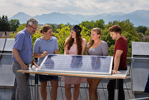 Studierende mit Professor auf Dachterrasse